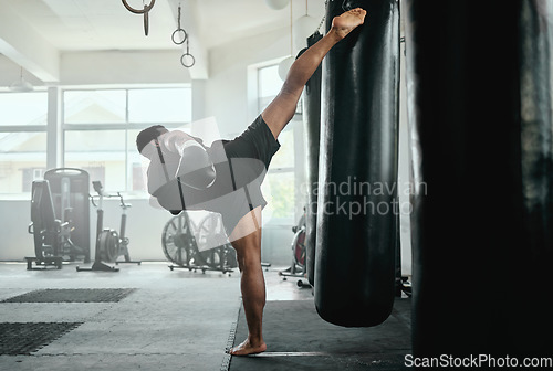 Image of Professional, fit and active male fighter training with a punching bag in a gym. kickboxer practicing, training and fitness exercise for competitive fight, tournament or competition in a health club