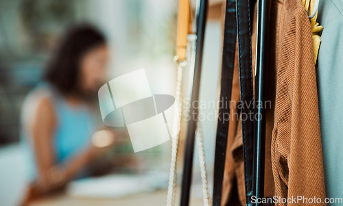 Image of Fashionable clothes, wardrobe display and boutique collection hanging on store rail with designer, stylist and woman working in the background. Closeup of trendy clothing design in a creative startup