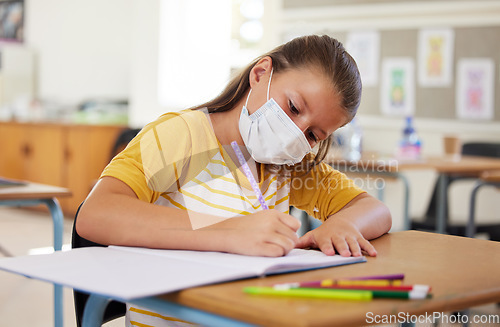 Image of School, education and learning with covid mask on girl face in classroom, writing or doing assignment alone. A dedicated, smart and disciplined learner in a lesson during pandemic while taking notes