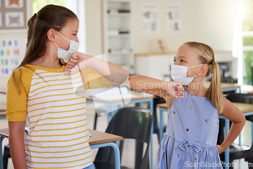 Image of Covid greeting, elbow bump and mask wearing with little girl students standing in class at school. Study, education and safety in a classroom with a female child and her friend bumping elbows