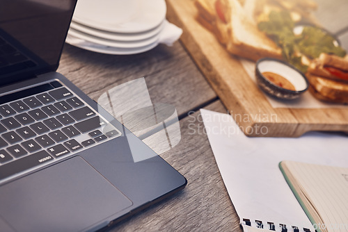 Image of Restaurant, cafe or coffee shop table as a workspace with a laptop, papers and food in the morning. Background or closeup of a remote and wooden work desk outdoors at a fast food place