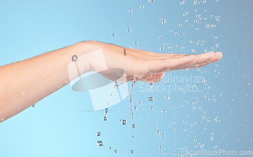 Image of Woman cleaning hands with water splash, shower and beauty for healthy skincare, personal hygiene and wellness on blue background. Closeup of water drops for washing hands, palm and body in bathroom