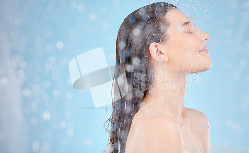 Image of Woman, water splash or showering on blue background in studio, house or home bathroom in hygiene maintenance or healthcare wellness. Beauty model, wet or skincare cleaning in morning grooming routine