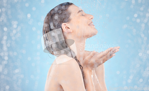 Image of Woman, water splash and showering in skincare grooming, hygiene maintenance and healthcare wellness on blue background. Smile, happy and washing beauty model in wet cleaning for dermatology self care