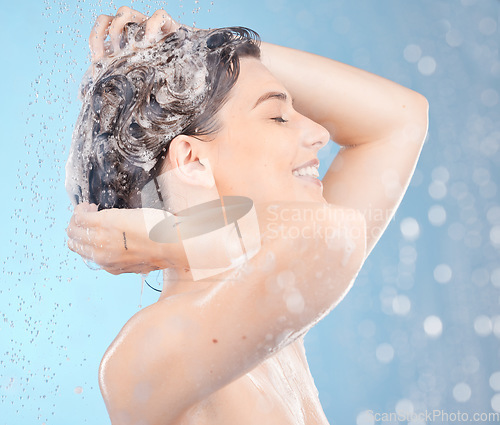 Image of Shower, woman in studio and washing hair, shampoo and scalp for healthy skincare, body beauty or water splash on blue background. Happy model cleaning head with soap, foam or under water in hair care