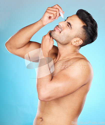 Image of Health, vision and man with eye drops for allergy on blue background for wellness, eye and optical care. Optometry, healthcare and young male apply liquid, drops and medicine in eyes for contact lens