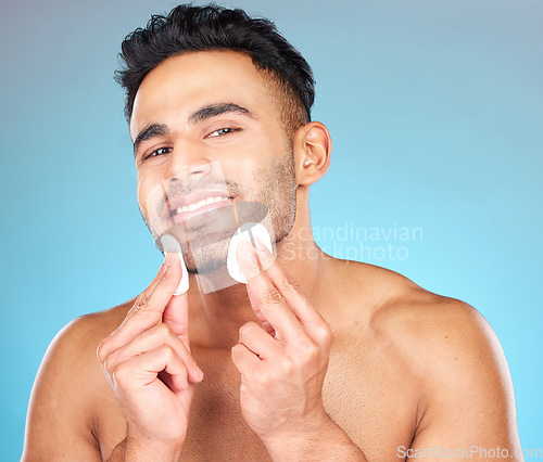 Image of Man, skincare portrait and cotton pad in studio for beauty, wellness or cosmetic self care with smile. Happy, model face and cottonwool for cleaning, cosmetics or healthy aesthetic by blue background