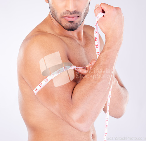 Image of Fitness, man and measure arm or bicep for bodybuilding strength and muscle growth or progress. Biceps, arms and fit or strong male weightlifter using tape measure to check development in a studio