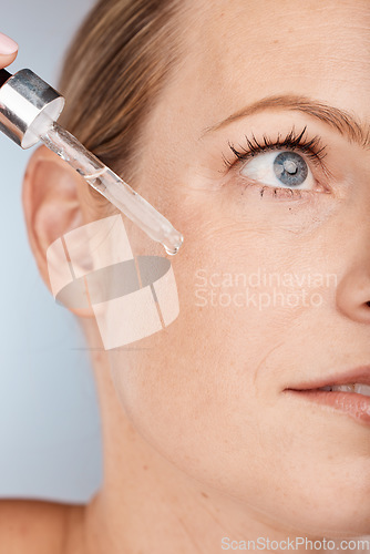 Image of Face, skincare and serum with a model woman in studio on a gray background to promote a cosmetic product. Facial, beauty and antiaging with a female applying oil to her skin for natural cosmetology