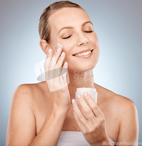 Image of Skincare, beauty and cream on face, woman on studio background for skin and body care. Happy, clean and fresh bathroom beauty routine for model. Sun protection application of anti aging sunscreen.