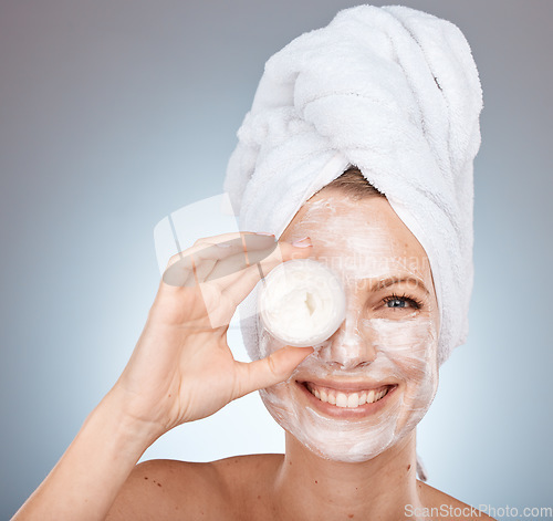 Image of Portrait, facial and skincare with a model woman in studio on a gray background to promote a skin product. Face, smile and container with a happy female posing for natural treatment or antiaging mask