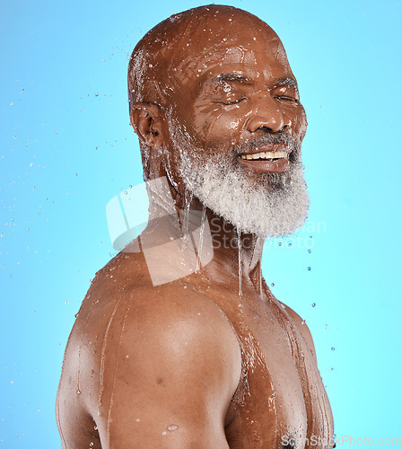Image of Studio, water and old man in a shower cleaning his face or body for skincare beauty or wellness on a blue background. Smile, healthy or happy elderly male model washing or relaxing with mock up space