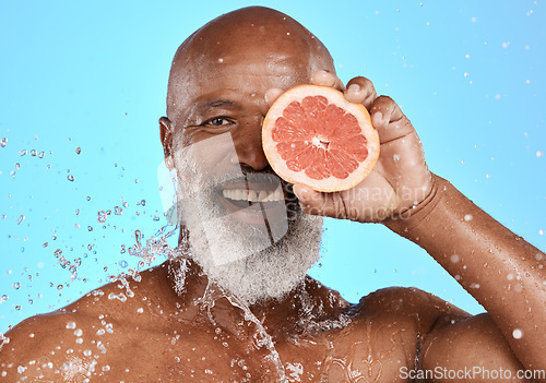 Image of Portrait, skincare or black man with grapefruit studio with water splash on blue background with mockup space. Smile, face or senior male model on healthy diet for beauty, detox or vitamin c benefits