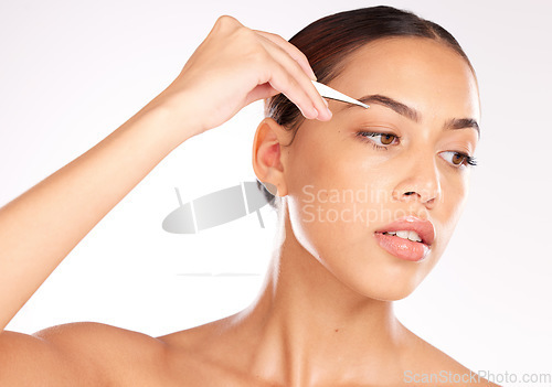 Image of Hair removal, model or woman with a tweezer for eyebrow beauty, skincare or grooming in studio on white background. Wellness, face and young relaxed girl plucking eyebrows in a self care routine