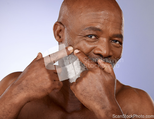 Image of Face, beauty and skincare with a senior black man checking his skin for a pimple or zit in studio on a purple background. Portrait, wellness and facial cleaning with a mature male posing for hygiene