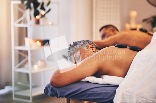 Image of Relax, massage and hot stone with a couple in a spa, lying on a table or bed for physical therapy. Rock, sleep and luxury with a senior man and woman in a health or wellness center for stress relief