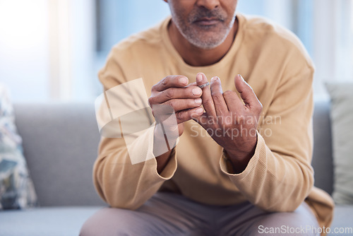 Image of Mature man, hands or touching wedding ring on sofa in house, home or marriage counseling in divorce, break up or loss. Sad, anxiety stress or mental health for widower or middle aged person with band