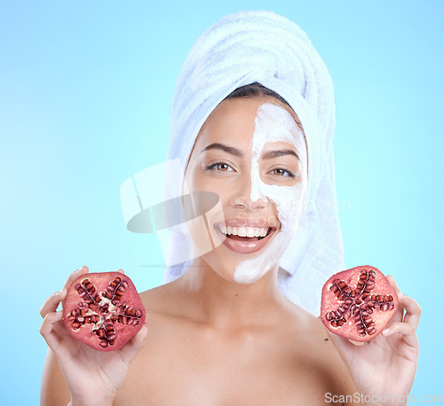 Image of Face mask, beauty skincare and woman with pomegranate in studio isolated on a blue background. Half facial mask, spa treatment and female model holding fruits for nutrition, vitamin c or healthy diet