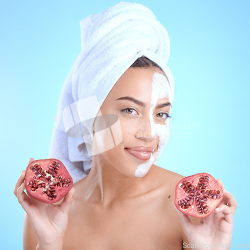 Image of Beauty cream, face and woman with pomegranate, skincare and vitamin c for health, wellness and towel after shower in blue studio background. Model portrait, fruit and skin care, detox or clean facial