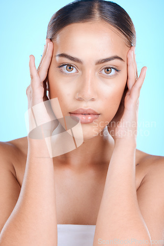 Image of Woman, skincare or touching face with hands on blue background in studio for dermatology self love, anti aging treatment or collagen. Facial portrait, Brazilian beauty model or eyes makeup cosmetics