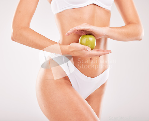 Image of Wellness, diet and hands with apple for slim body, self care and healthy lifestyle on white background studio. Fitness, exercise and abdomen of woman with fruit for vitamins, nutrition and weightloss