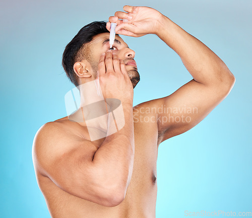 Image of Man, eye drops and vision in studio for healthcare, eyesight and medical product for allergies. Shirtless model, liquid solution and eyes to stop allergy, self care and wellness by blue background