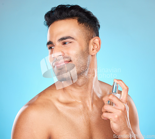 Image of Man, smile and perfume for aroma, fragrance and natural beauty against blue studio background. Young male, confident gentleman and cologne for manly scent, wellness and to smell good for hygiene.