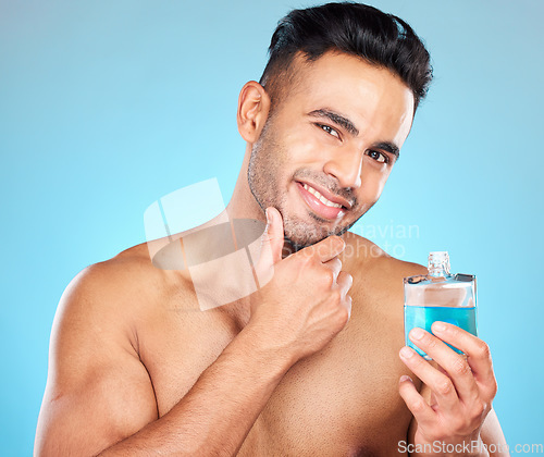 Image of Beauty, cosmetics and man with cologne in studio on blue background for wellness, self care and luxury. Skincare, grooming and Indian male model with perfume, fragrance and scent in bottle