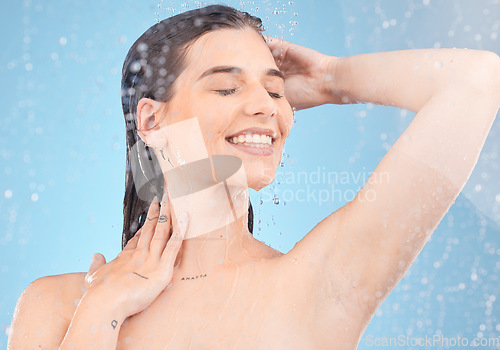 Image of Woman, shower and cleaning for hygiene, bodycare and beauty with water on a blue studio background. Skincare, body care and female showering or washing and cleansing the skin in grooming routine