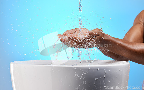 Image of Black man, water splash and washing hands on blue background in studio hygiene maintenance, bacteria cleaning or healthcare wellness. Zoom, model and wet sink for skincare grooming in house bathroom