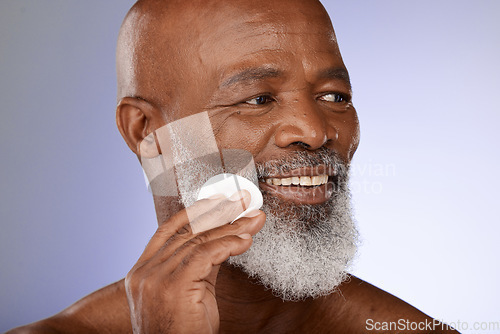 Image of Face, skincare and antiaging with a senior black man exfoliating his skin in studio on a gray background. Beauty, cleaning and cleansing with a mature male using a cotton pad for natural treatment