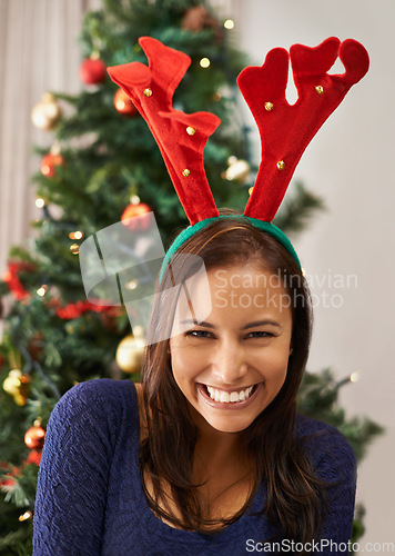 Image of Portrait of happy woman, christmas and reindeer hat at home in celebration, winter holidays or joy in Spain. Excited young lady wearing festive headband with antlers to celebrate xmas season in house