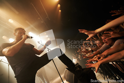 Image of Band, singer and musician with fans, crowd and excited audience at concert, rock music festival and stage performance at nightclub. Man, artist and singing on mic at live show, event and techno party