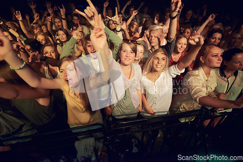 Image of Concert, music festival and crowd with rock hands sign for singing, dance and night event, performance and celebration in dark. Group of people, audience and gen z lifestyle techno, rave and party