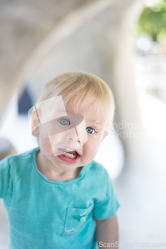 Image of Portrait of cute little infant baby boy child playing on outdoor playground. Toddler plays on school or kindergarten yard.