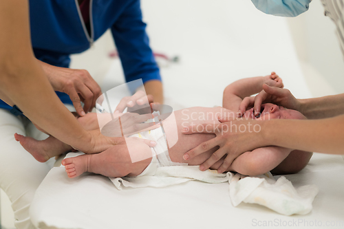 Image of Baby beeing vaccinated by pediatrician in presence of his mother. Preventive vaccination against Diphtheria, whooping cough, tetanus, hepatitis, haemophilus influenzae, pneumococcus, poliomyelitis