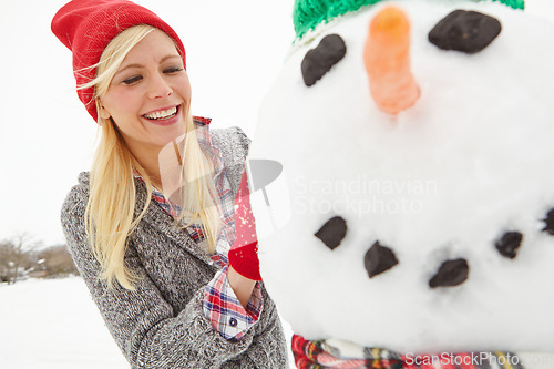 Image of Winter, snow and woman building a snowman outdoors during Christmas in England with happiness. Smile, festive season and xmas snow man being built by a happy female outdoors in cold weather