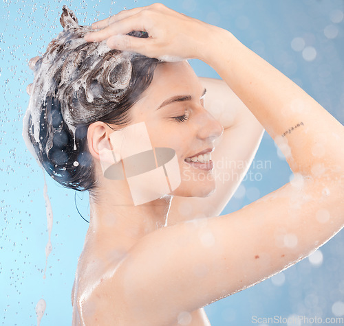 Image of Woman, shampoo and shower for hair care, clean or hygiene on blue studio background. Young female, girl or lady wet, water or bubbles for natural beauty, morning routine or skincare to relax or smile