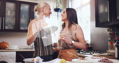 Image of Lesbian couple, champagne and LGBTQ with happy smile, love and cooking in kitchen and hosting a party in home. Women, partner and alcohol drinks in house with happiness, gay and drink with romance