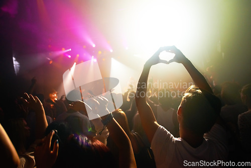 Image of Crowd at concert, music and watch band performance, music festival, light and energy with audience back view. People dance with hands in heart shape, musician on stage and festival in Florida.