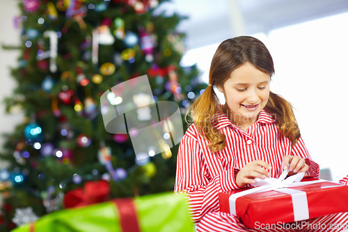 Image of Girl opening gift box for Christmas at family home, excited and happy with holiday spirit and celebration with present. Young child with gift, happiness and festive mood, tradition and celebrate.