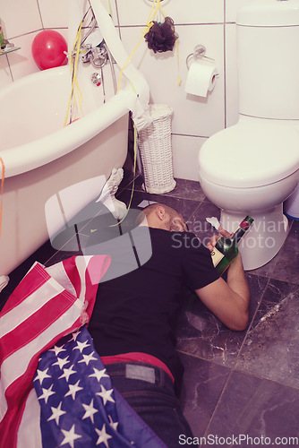 Image of Party, hangover and drunk man in bathroom sleeping after celebration, festival and house party in usa. After party, alcohol and male on floor by toilet of social event, new years eve and house party