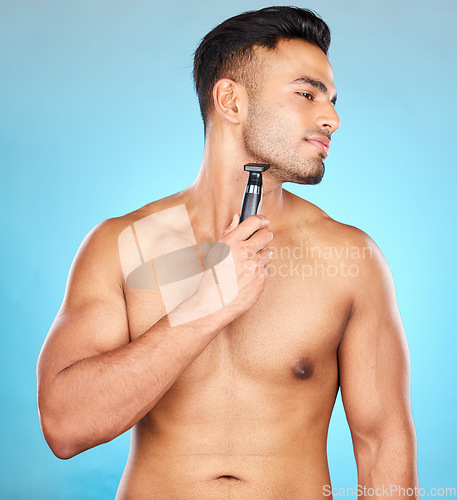 Image of Studio, hair removal or model shaving beard or grooming his face for beauty or facial skincare wellness. Relaxing, blue background or healthy man cleaning his face with electric blade machine