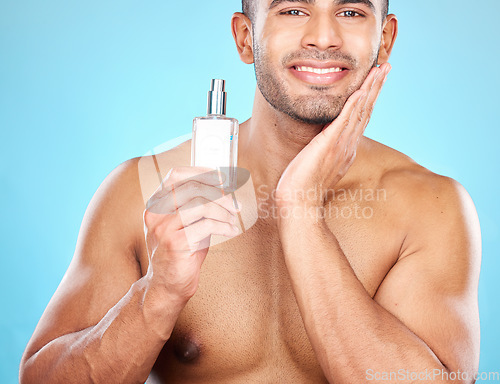 Image of Cologne, grooming and face of a man for skincare, beauty wellness and luxury cosmetics against a blue background in studio. Self care, smile and portrait of a model with facial perfume product