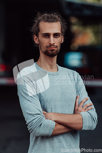 Image of Portrait of a young successful businessman with crossed arms in front of the company