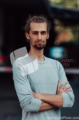 Image of Portrait of a young successful businessman with crossed arms in front of the company