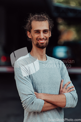 Image of Portrait of a young successful businessman with crossed arms in front of the company