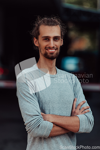 Image of Portrait of a young successful businessman with crossed arms in front of the company