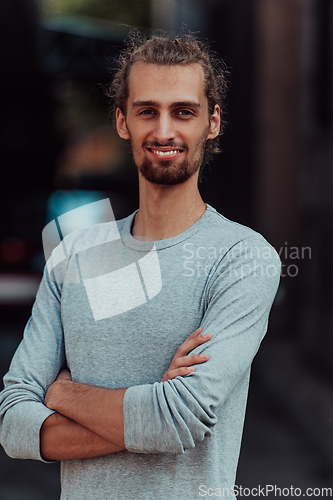 Image of Portrait of a young successful businessman with crossed arms in front of the company