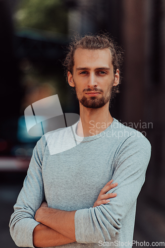 Image of Portrait of a young successful businessman with crossed arms in front of the company